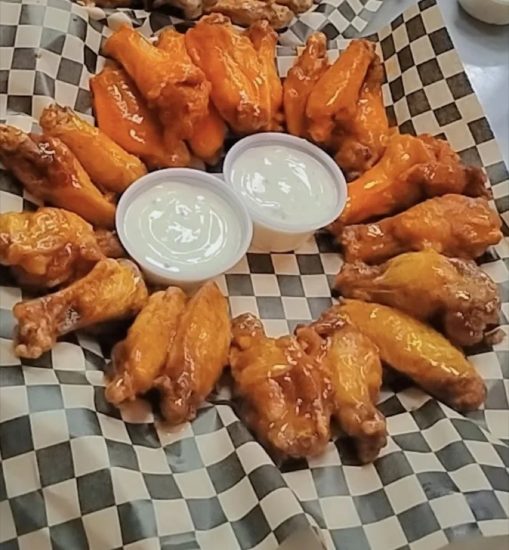 Basket of sauced wings with ranch on checkered paper at IST NOLA